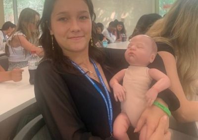 Bailey holding a baby doll at her nursing immersion program.