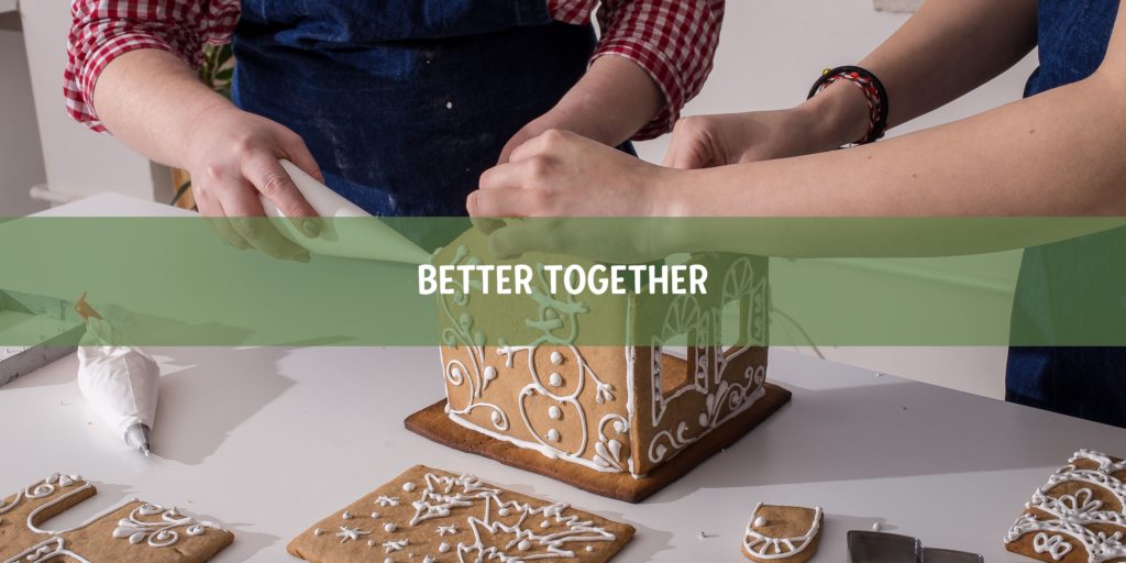 Mom and child making a gingerbread house with a "better together" slogan on a green banner.