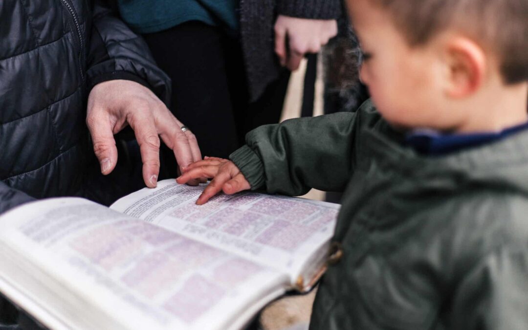 How caring for the widows and orphans impacts your church. Little boy holding open Bible with his parent on the other side.
